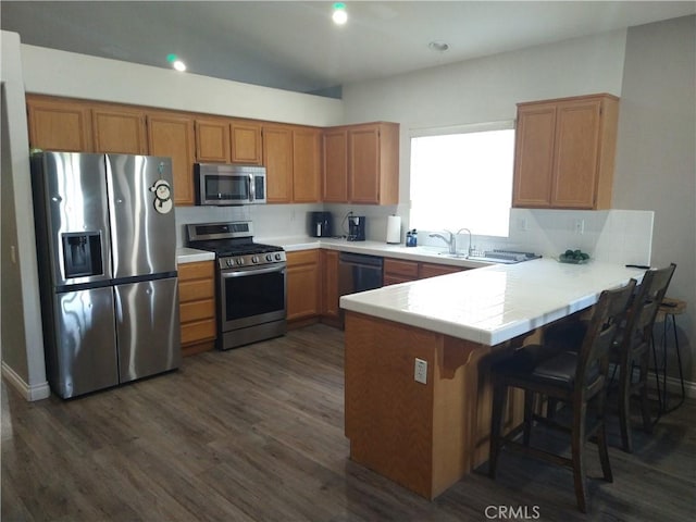 kitchen featuring sink, a breakfast bar, stainless steel appliances, dark hardwood / wood-style floors, and kitchen peninsula