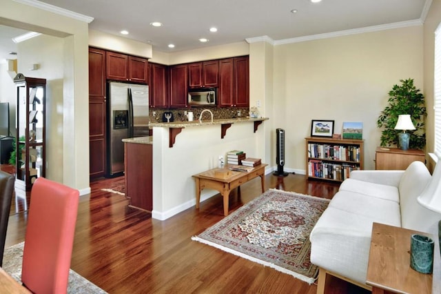 kitchen with dark hardwood / wood-style flooring, a kitchen bar, kitchen peninsula, and appliances with stainless steel finishes