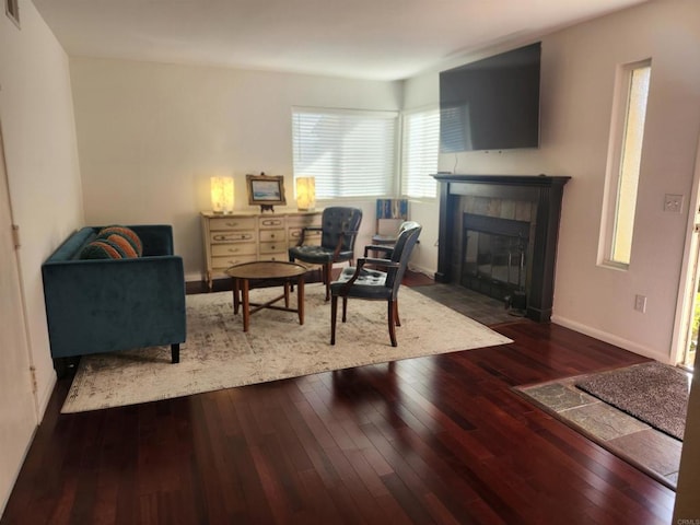 living room with dark wood-type flooring and a tiled fireplace