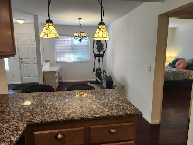 kitchen with dark hardwood / wood-style floors, decorative light fixtures, a chandelier, and dark stone countertops