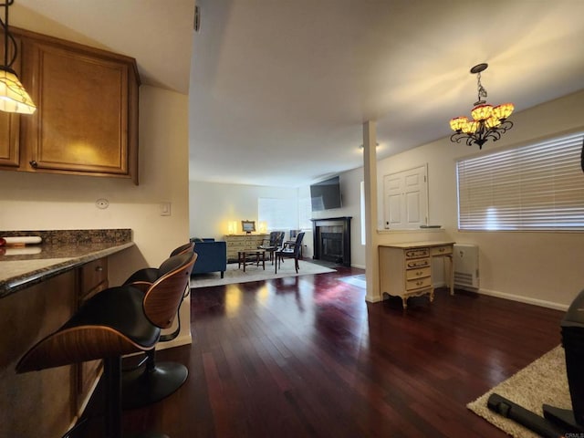 interior space featuring dark wood-type flooring, a fireplace, and a notable chandelier