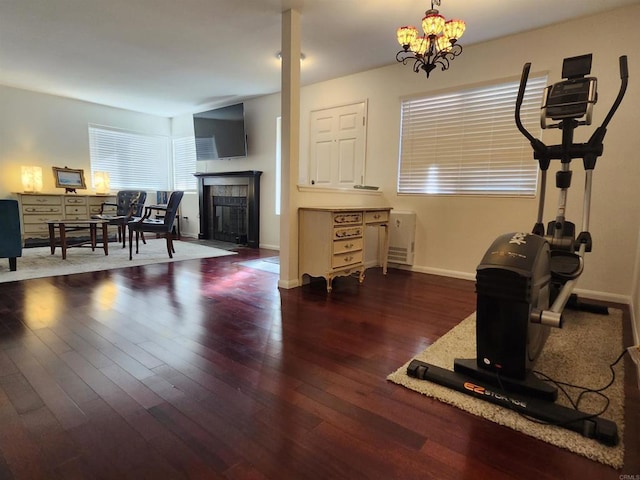 exercise room with an inviting chandelier, a fireplace, and dark hardwood / wood-style floors