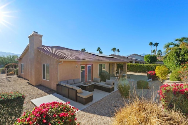 rear view of property featuring a patio, an outdoor living space with a fire pit, and solar panels