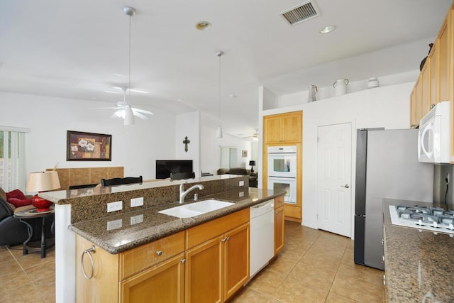 kitchen featuring ceiling fan, sink, dark stone countertops, white appliances, and light tile patterned floors