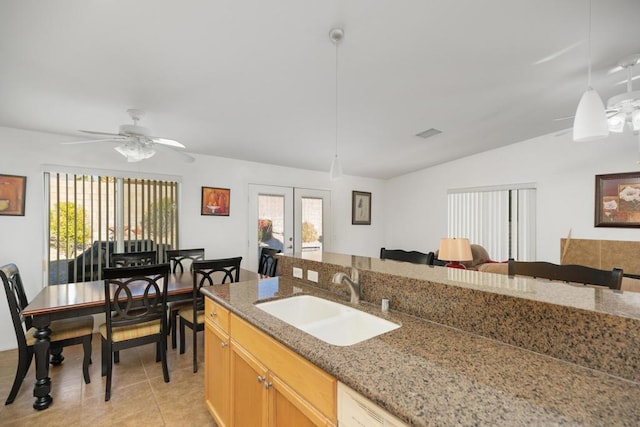 kitchen featuring ceiling fan, french doors, sink, hanging light fixtures, and light stone counters