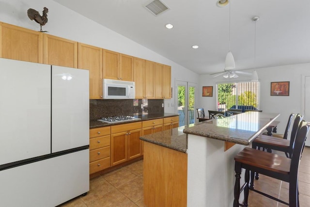 kitchen featuring white appliances, hanging light fixtures, vaulted ceiling, ceiling fan, and a kitchen island