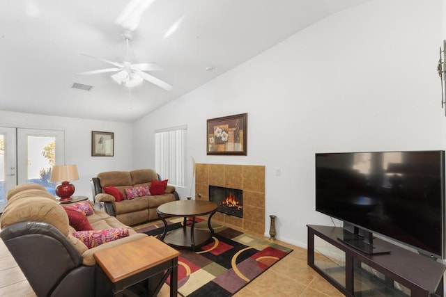 tiled living room featuring a tile fireplace, ceiling fan, french doors, and lofted ceiling