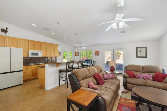 tiled living room with ceiling fan, french doors, and lofted ceiling