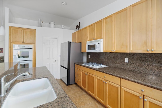 kitchen featuring dark stone countertops, sink, and white appliances