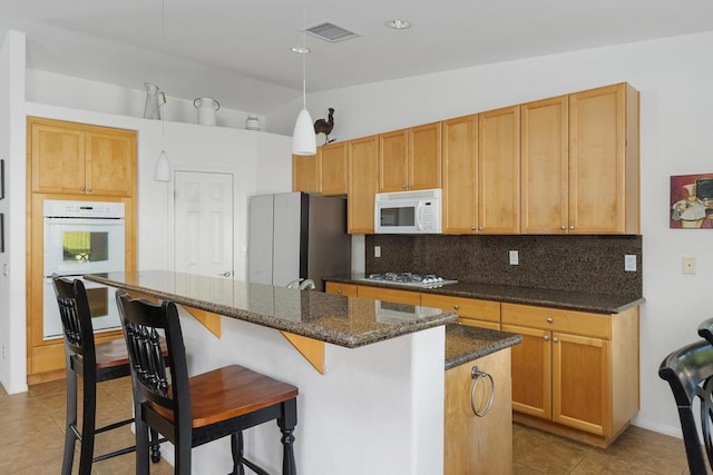 kitchen with a center island, tasteful backsplash, pendant lighting, vaulted ceiling, and white appliances