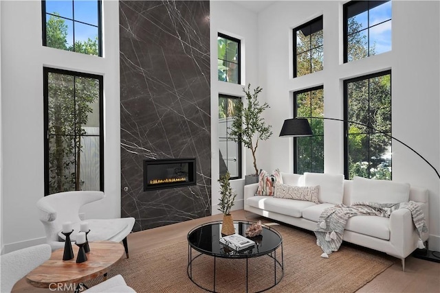 living room featuring hardwood / wood-style floors, a towering ceiling, tile walls, and a premium fireplace