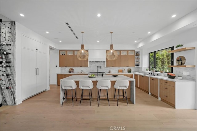 kitchen featuring a kitchen bar, a large island, light hardwood / wood-style floors, and decorative light fixtures