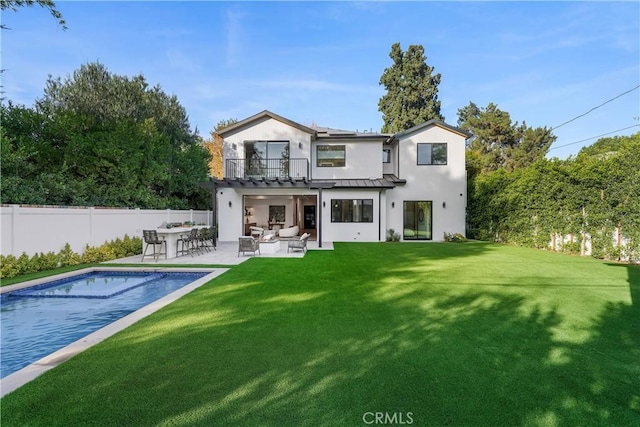 rear view of house with a fenced in pool, an outdoor hangout area, a balcony, a yard, and a patio