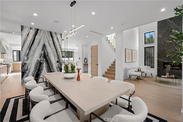 dining space with a high end fireplace, a chandelier, and light wood-type flooring