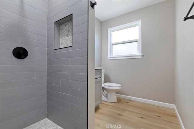 bathroom featuring tiled shower, vanity, wood-type flooring, and toilet