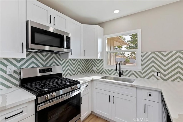 kitchen with tasteful backsplash, white cabinetry, sink, and stainless steel appliances