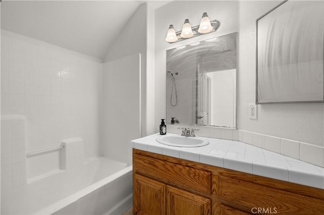 bathroom with washtub / shower combination, vanity, and vaulted ceiling