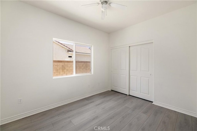 unfurnished bedroom featuring ceiling fan, light wood-type flooring, and a closet