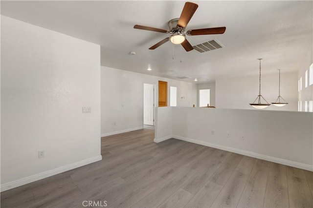 empty room featuring hardwood / wood-style floors, ceiling fan, and a healthy amount of sunlight