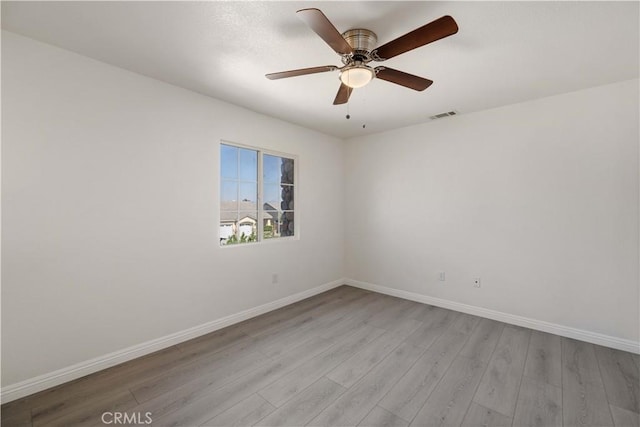 empty room with ceiling fan and light hardwood / wood-style flooring