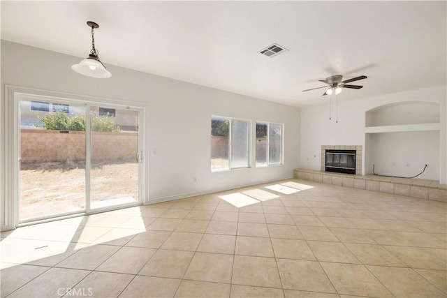 unfurnished living room with ceiling fan, light tile patterned flooring, and a tile fireplace