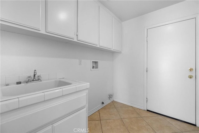 laundry room featuring hookup for a washing machine, light tile patterned floors, cabinets, and sink