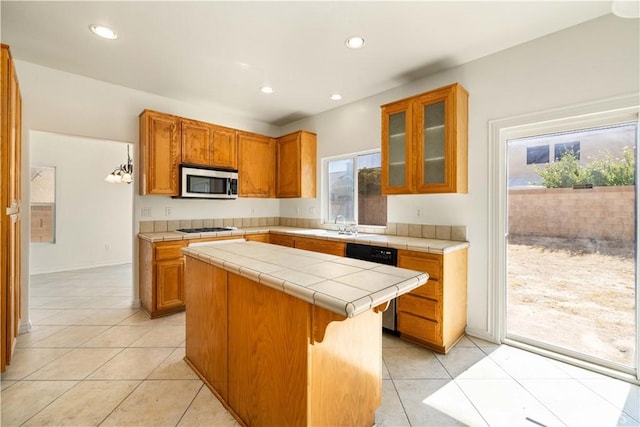 kitchen with a wealth of natural light, a center island, tile counters, and appliances with stainless steel finishes