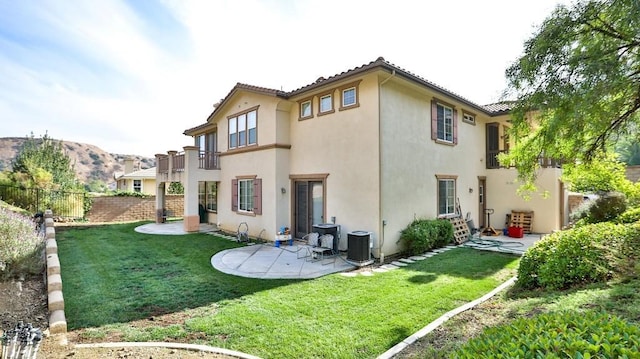 rear view of property featuring a balcony, a patio area, and a lawn