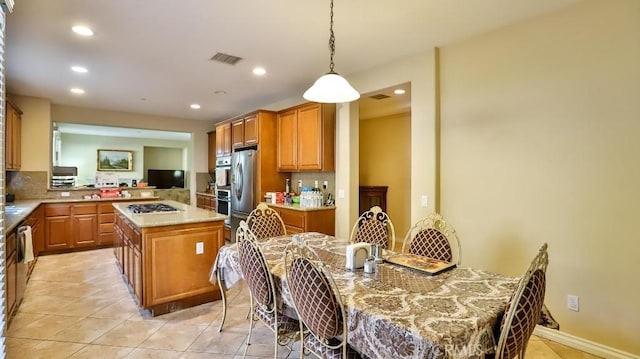 kitchen with kitchen peninsula, tasteful backsplash, light tile patterned floors, a center island, and hanging light fixtures