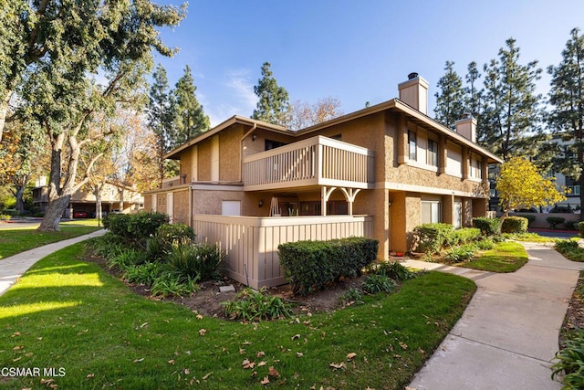 view of front facade featuring a balcony and a front lawn