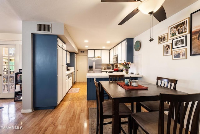 kitchen featuring white cabinets, ceiling fan, tasteful backsplash, light hardwood / wood-style floors, and stainless steel appliances