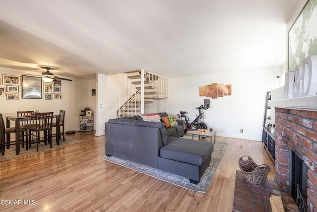 living room featuring a fireplace, wood-type flooring, and ceiling fan