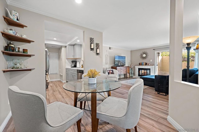 dining room featuring light wood-type flooring, crown molding, and sink