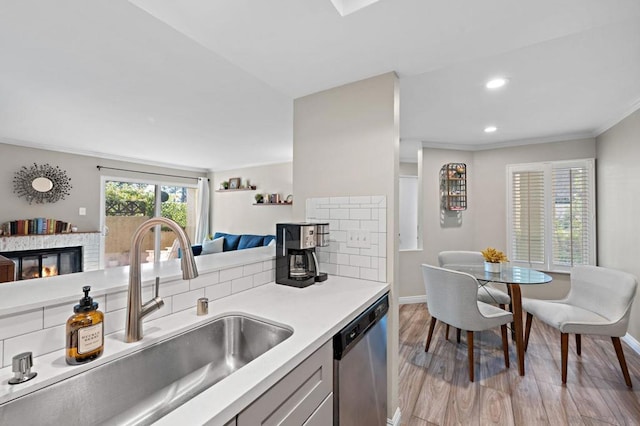 kitchen with tasteful backsplash, crown molding, sink, dishwasher, and light hardwood / wood-style floors