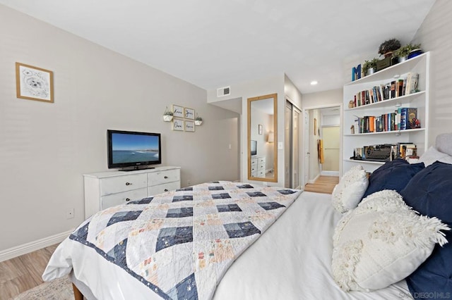 bedroom featuring ensuite bathroom and light hardwood / wood-style flooring