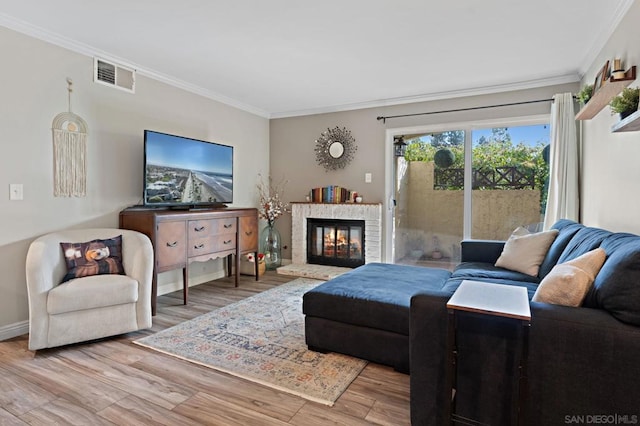 living room with light wood-type flooring, a brick fireplace, and ornamental molding