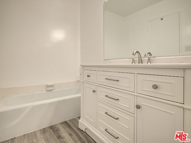 bathroom featuring hardwood / wood-style floors, vanity, and a washtub