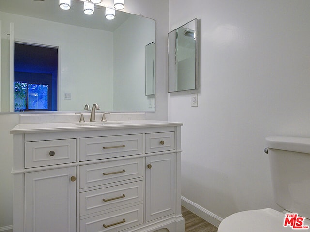 bathroom featuring wood-type flooring, vanity, and toilet