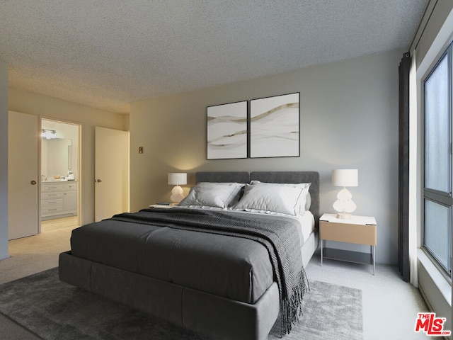 bedroom with light colored carpet, a textured ceiling, and connected bathroom