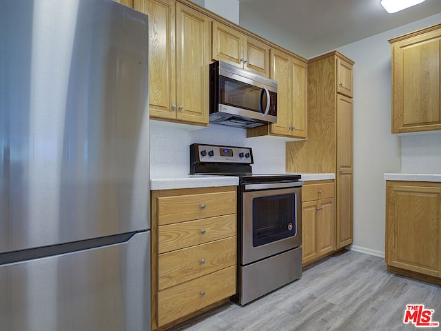 kitchen featuring decorative backsplash, light brown cabinetry, stainless steel appliances, and light wood-type flooring