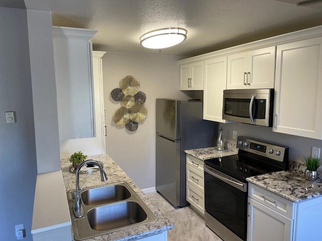 kitchen featuring appliances with stainless steel finishes, sink, white cabinets, and a textured ceiling