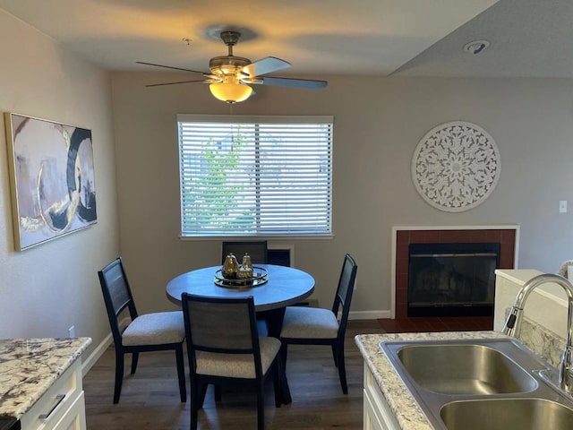 dining room with dark hardwood / wood-style flooring, sink, a tile fireplace, and ceiling fan