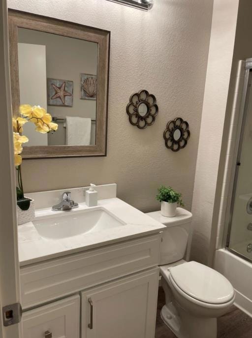 full bathroom with vanity, hardwood / wood-style floors, enclosed tub / shower combo, and toilet