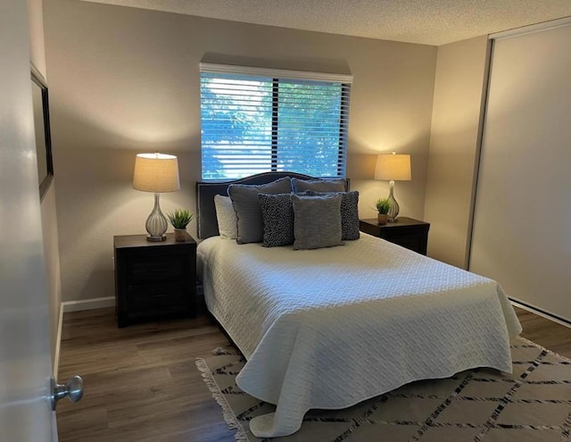 bedroom featuring a textured ceiling, dark hardwood / wood-style flooring, and a closet