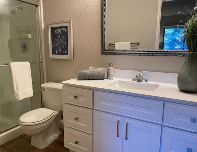 bathroom with hardwood / wood-style floors, vanity, toilet, and walk in shower