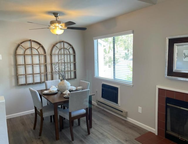 dining room featuring a tile fireplace, ceiling fan, a baseboard heating unit, a wall unit AC, and dark hardwood / wood-style floors