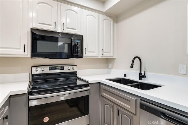 kitchen with appliances with stainless steel finishes, gray cabinets, white cabinetry, and sink