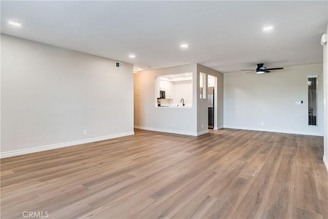 unfurnished living room with light wood-type flooring and ceiling fan