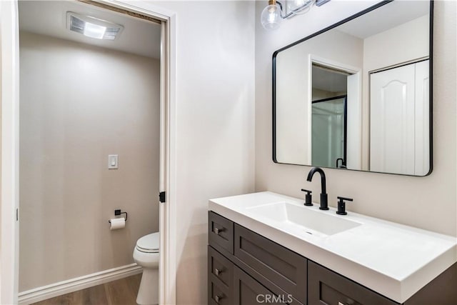 bathroom featuring vanity, hardwood / wood-style flooring, and toilet