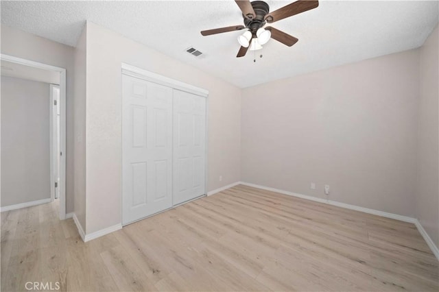 unfurnished bedroom with ceiling fan, light hardwood / wood-style floors, a textured ceiling, and a closet